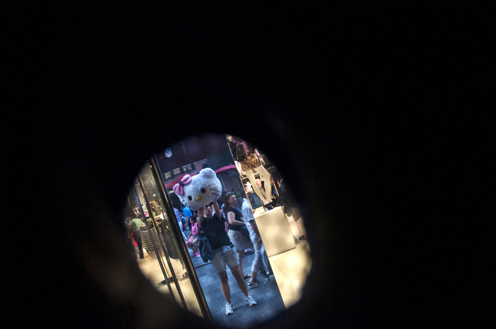 New York, United States. Self portrait right through an eye hole in the head of my Hello Kitty costume. Immigrants dressed up as entertainment symbols ask for donations after posing for pictures in Times Square. 2014 ©Joana Toro.